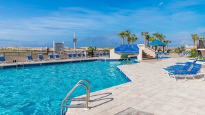 A pool area with clear blue water, lounge chairs, and a view of the ocean.