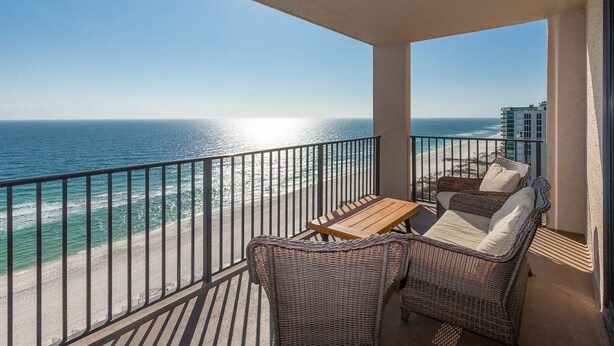 Ein Balkon mit Korbmöbeln und Blick auf den Strand und den Ozean.