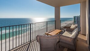 Een balkon met rieten meubilair en uitzicht op het strand en de oceaan.