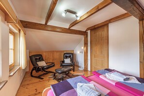 A room with wooden beams, a massage table, two leather chairs, and a window with curtains. - Vineyard Cottage Stepan (Crnomelj)