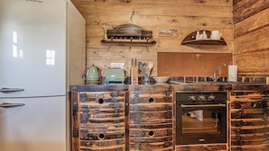Een landelijke keuken met houten kastjes, een inbouwoven en een witte koelkast.