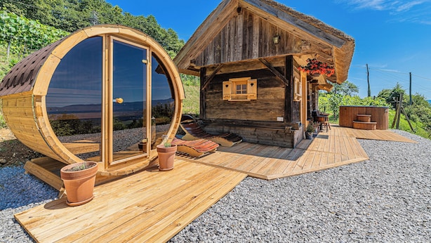 Een houten blokhut met een ronde constructie, een houten terras en een klein zitgedeelte buiten.