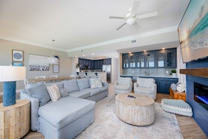 A modern living room with a sectional sofa, a round coffee table, and a fireplace.