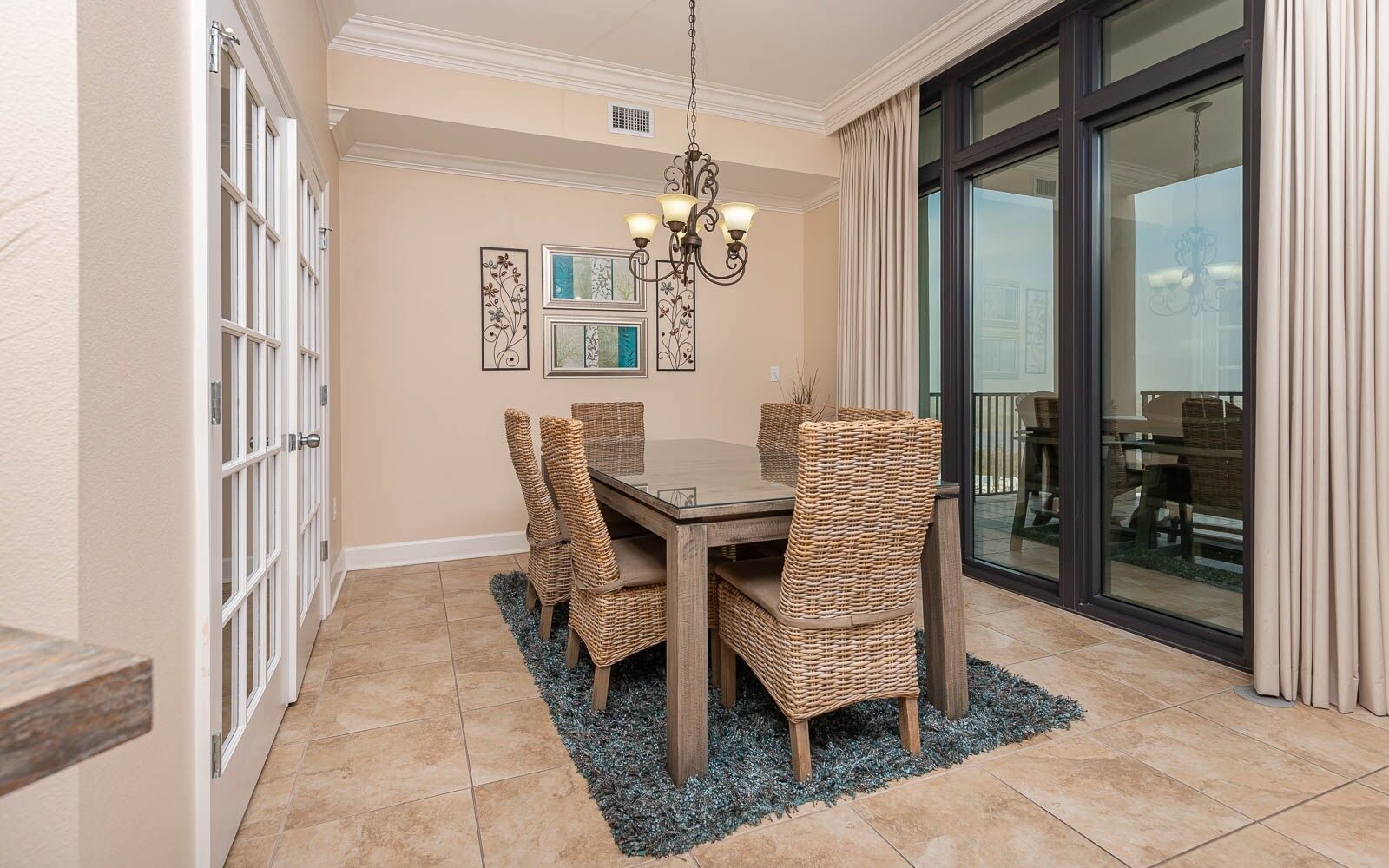 A dining area with a table and chairs, a chandelier, and a view through a glass door.