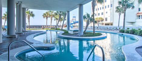 A pool area with a curved design, palm trees, and lounge chairs.