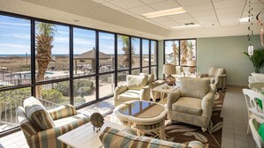 A spacious room with large windows, a pool view, and a variety of seating arrangements.