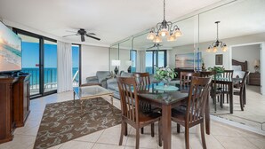 A spacious living area with a balcony, a dining area with a glass table, and a modern kitchen.