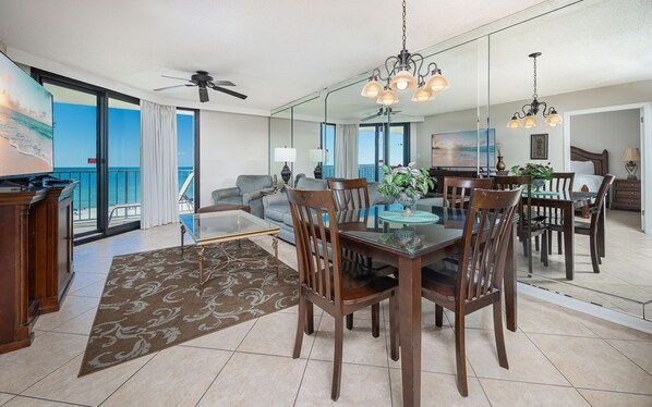 Een ruime woonkamer met balkon, een eetgedeelte met glazen tafel, en een moderne keuken.