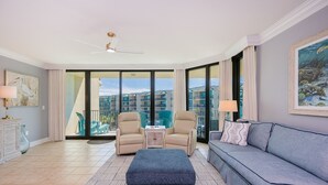A spacious living room with a large sofa, two armchairs, a coffee table, and a ceiling fan.