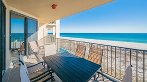 Un balcon avec vue sur la plage, une table et des chaises.