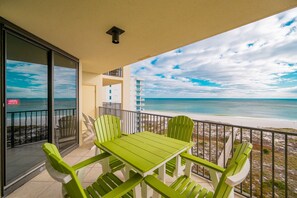 A balcony with a table and chairs, overlooking a beach and ocean. - Phoenix Viii 8802 2 Bedroom Condo (Orange Beach)