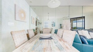 Un coin repas avec une table en bois rustique, des chaises en osier et un canapé bleu.