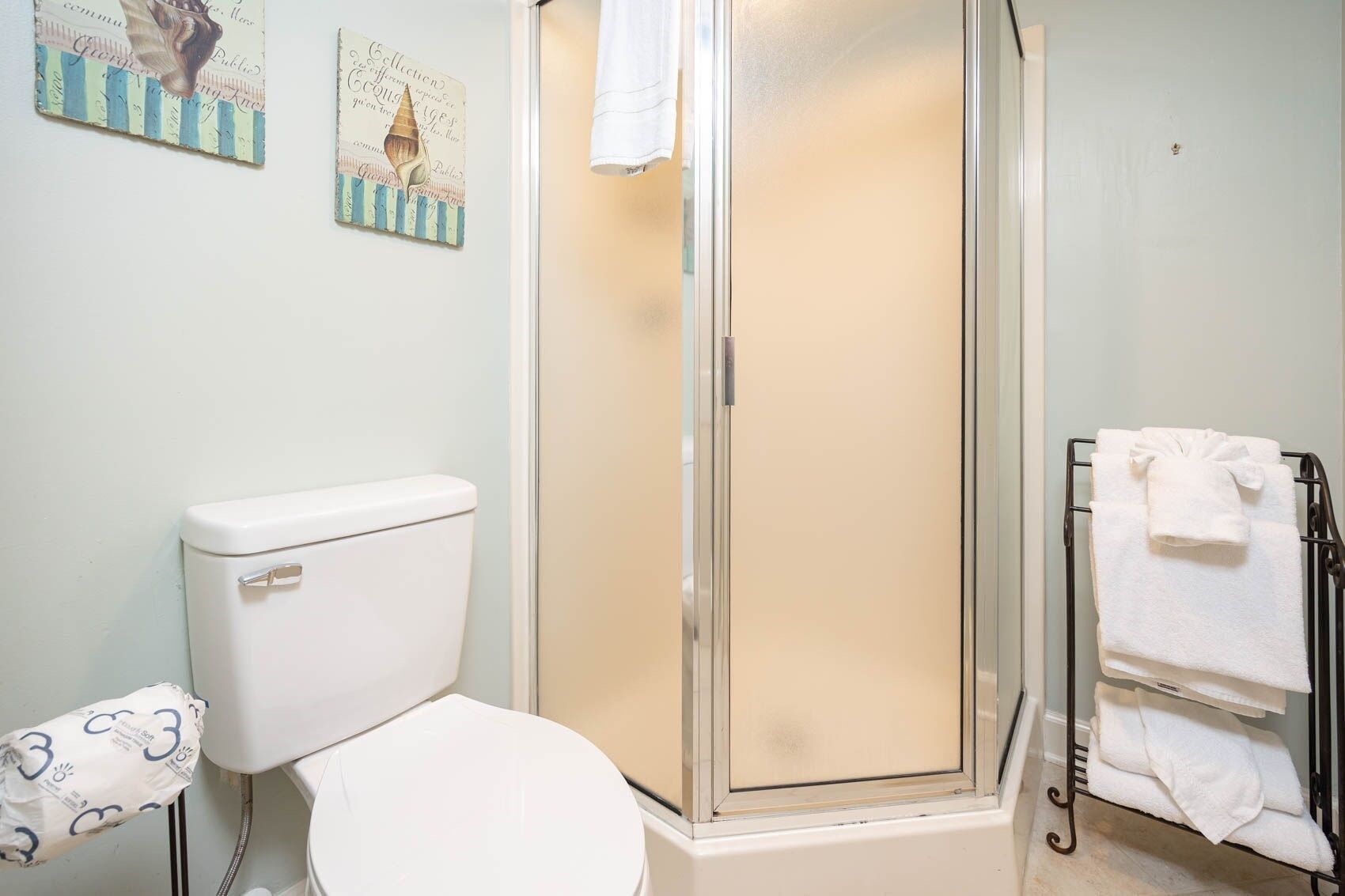 Une salle de bain comprenant des toilettes, une douche à parois de verre et un porte-serviettes.