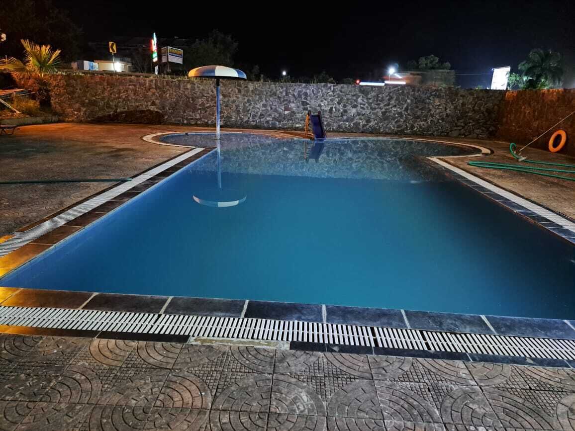 A swimming pool with a stone wall and a tiled deck.