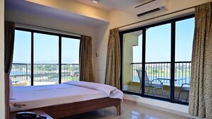 A hotel room with a bed, a desk, and a balcony with a table and chairs. - Hotel Vegas (Khandala)