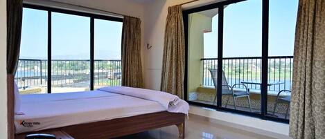 Una habitación de hotel con una cama, un escritorio y un balcón con mesa y sillas.
