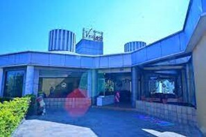 A building with a modern architectural design, featuring a prominent entrance and a sign above the door. - Hotel Vegas (Khandala)