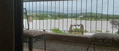 A balcony with a view of a river and distant hills.