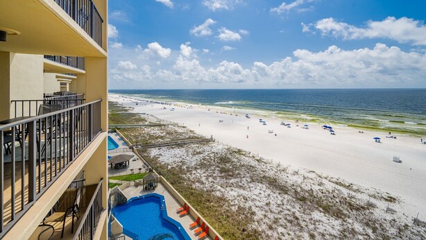 A beach view from a hotel balcony with a swimming pool and outdoor seating. - Phoenix Iii 3074 2 Bedroom Condo (Orange Beach)