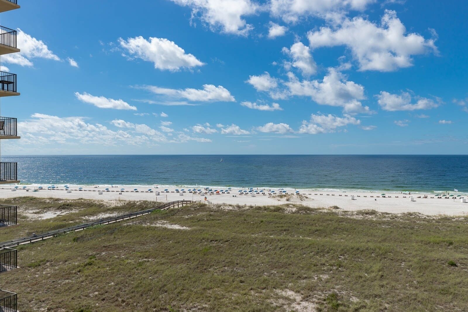 Utsikt över stranden från en byggnad med en balkong, en sandstrand och havet.
