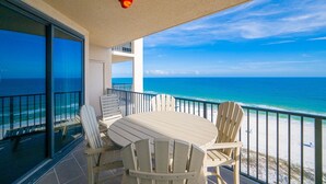 A balcony with a table and chairs, overlooking a beach and ocean. - Phoenix X 1202 1 Bedroom Condo (Orange Beach)