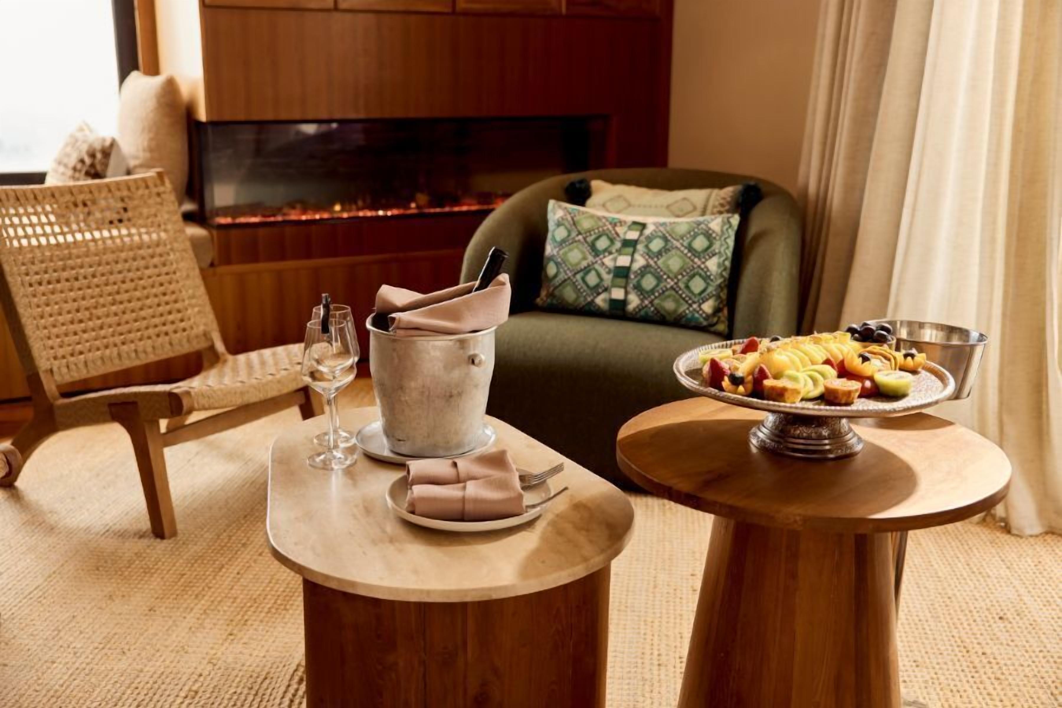 A cozy living room with a fireplace, a dining table with a fruit platter, and a comfortable seating area.