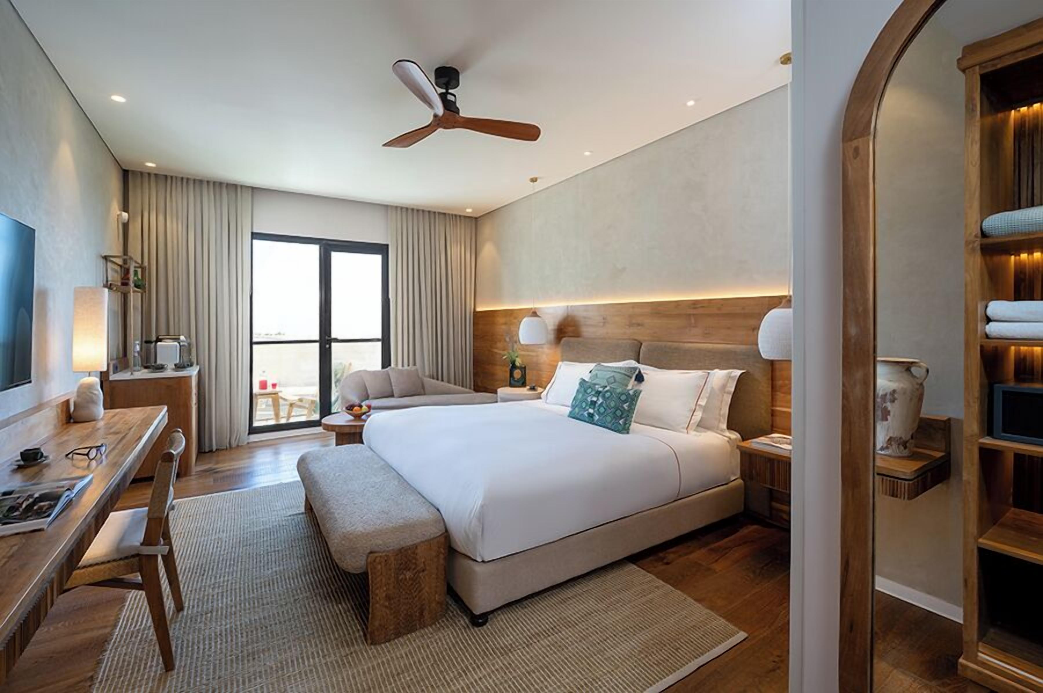 A hotel room with a large bed, bedside tables, a desk, and a chair.