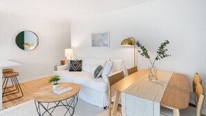 Ein modernes Wohnzimmer mit einem weißen Sofa, einem runden Couchtisch und einem Esstisch mit Stühlen.