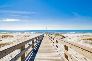 A wooden boardwalk leading to the beach with a clear sky.