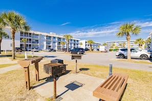 A parking lot with a row of parked cars, a wooden bench, and a building with multiple balconies in the background. - 🌊 Beachfront Bliss on the Fort Morgan Peninsula – Chic Condo with Panoramic Gulf Views (Gulf Shores)