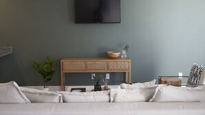 A modern living room with a flat-screen TV mounted on the wall, a wooden console table with decorative items, and a sofa with cushions. - ✨ Stylish Beach Condo – Sleeps 6 in family friendly Gulf Place, Santa Rosa Beach (Santa Rosa Beach)