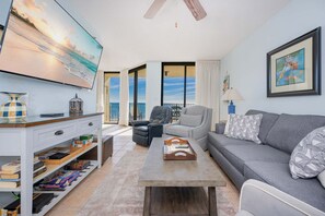 A living room with a sofa, a coffee table, a TV, and a bookshelf. - Phoenix Viii 8705 1 Bedroom Condo (Orange Beach)