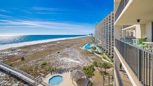 A hotel with a pool, beach view, and multiple balconies.