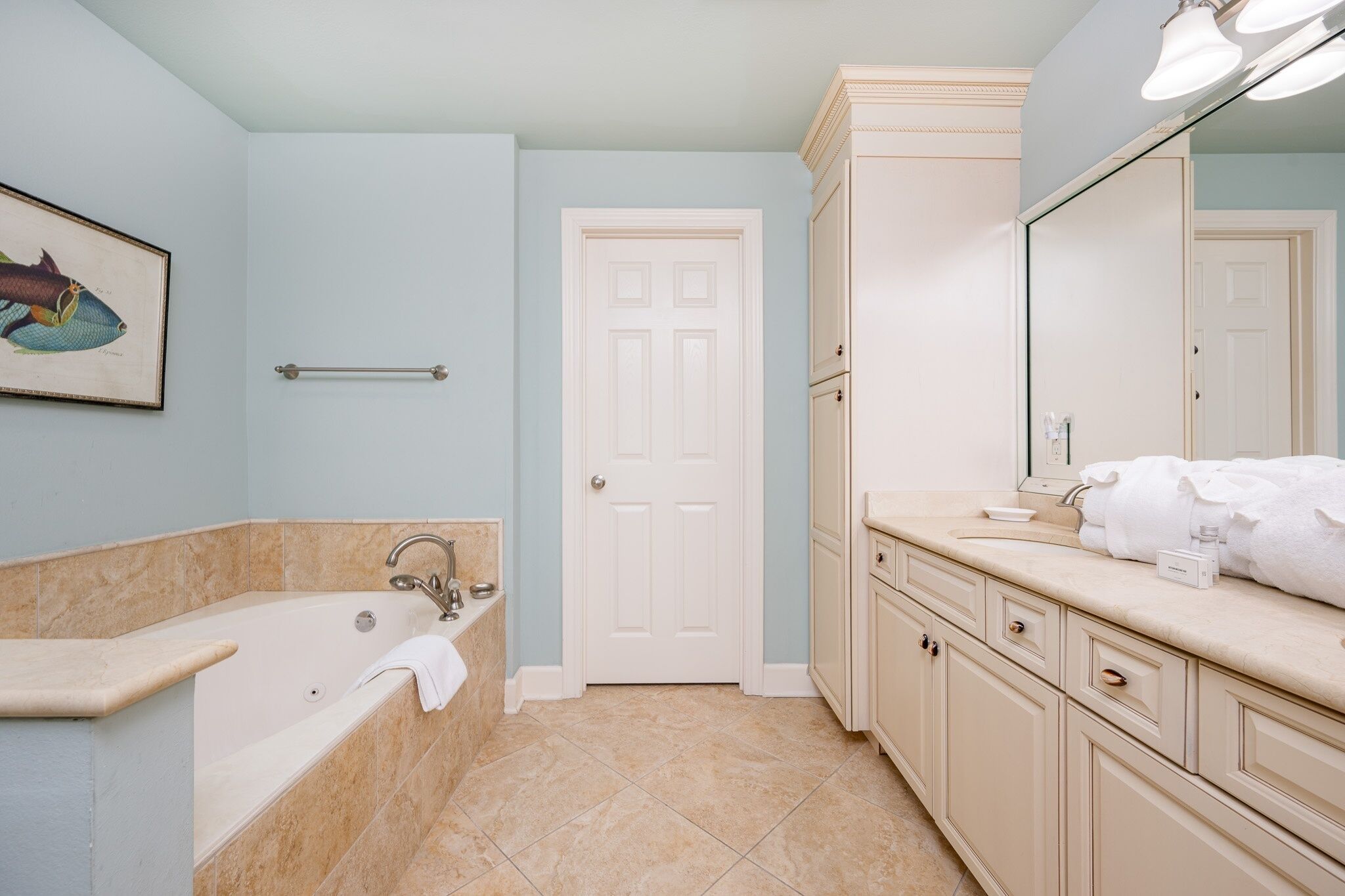 A bathroom with a bathtub, a sink, a mirror, and a door.