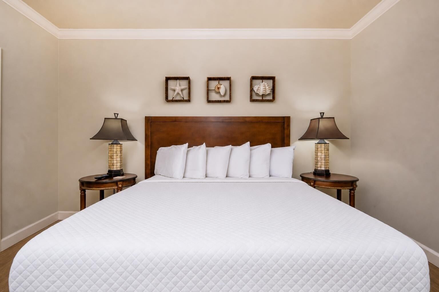 A hotel room with a large bed, two bedside lamps, and three wall-mounted decorative items.