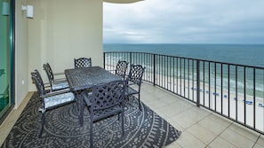 Varanda com mesa e cadeiras, tapete estampado e vista para o mar.