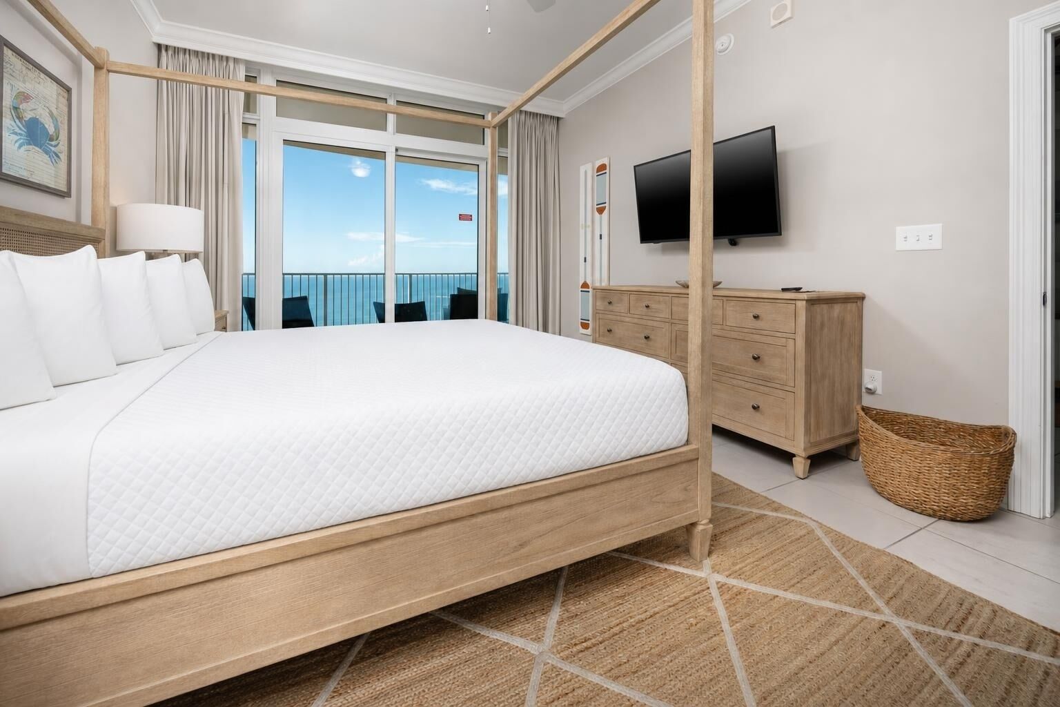 Una habitación de hotel con una cama grande, un aparador de madera, televisión y vistas al océano.