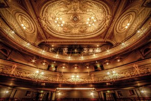An ornate theater interior with a grand ceiling, multiple balconies, and elaborate chandeliers. - Church View (Buxton)