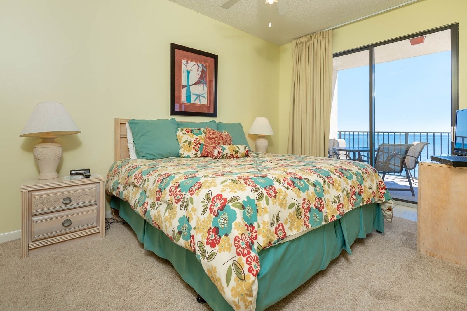 A bedroom with a bed, a nightstand, a TV, and a balcony with a view.