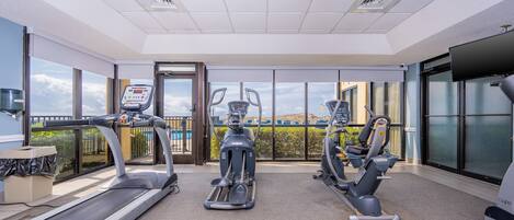 Un gimnasio con cintas de correr, elípticas y una bicicleta estática.