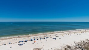 Ein Strand mit blauem Himmel, sandigem Ufer und Sonnenschirmen.
