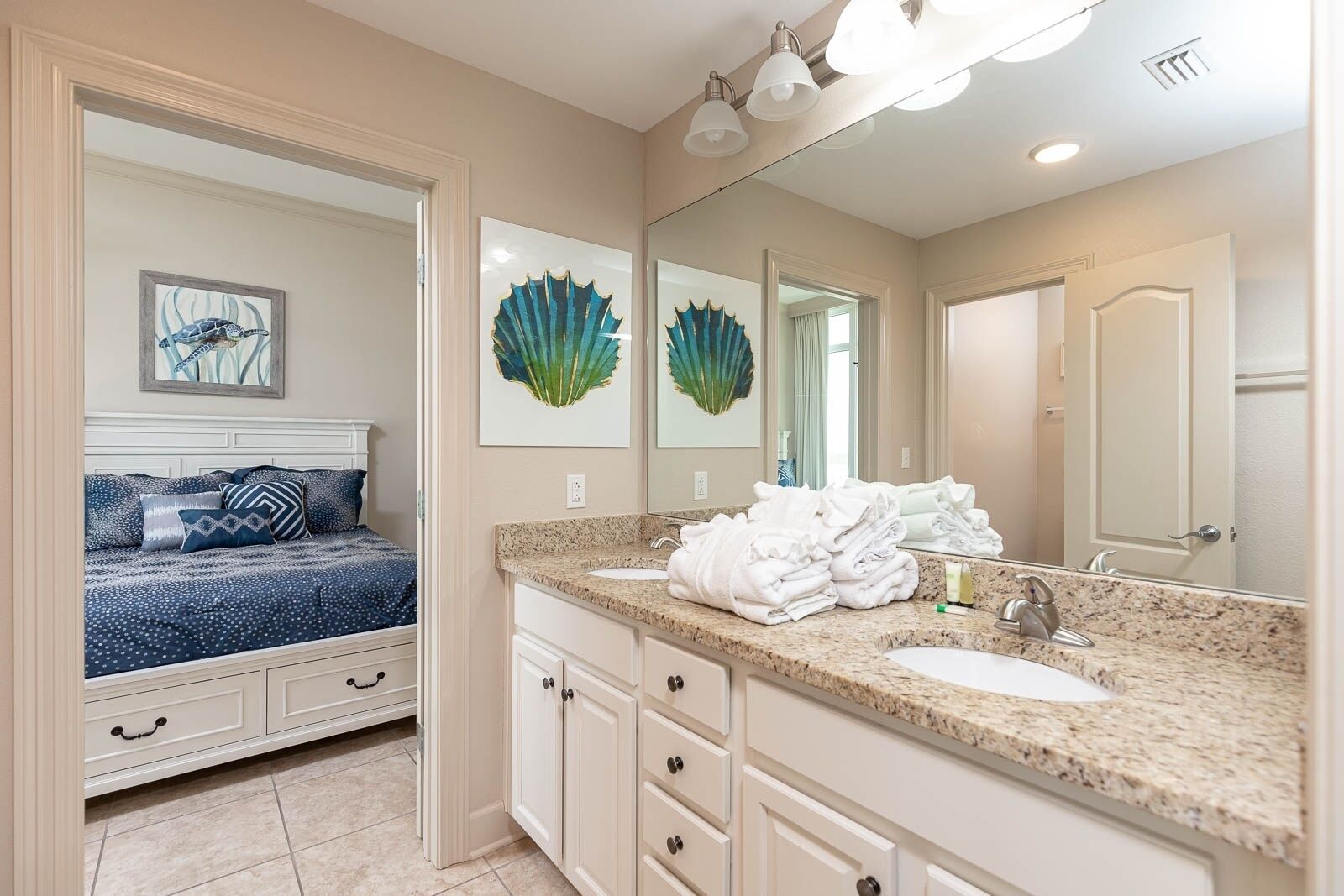 A bedroom with a bed, a bathroom with a sink and mirror, and a hallway with a door.