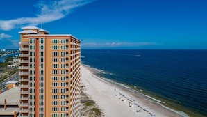 A high-rise hotel with multiple balconies overlooking a beach.