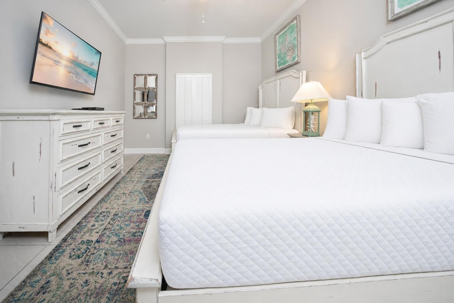 A hotel room with a large bed, a dresser, a television, and a door.
