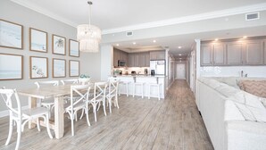 Una cocina amplia con suelo de madera, armarios blancos y una isla central con taburetes.