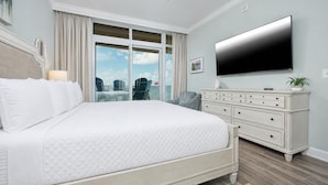 A bedroom with a large bed, a dresser, a flat-screen TV, and a view of the outdoors. - Phoenix Orange Beach Ii 1002 3 Bedroom Condo (Orange Beach)