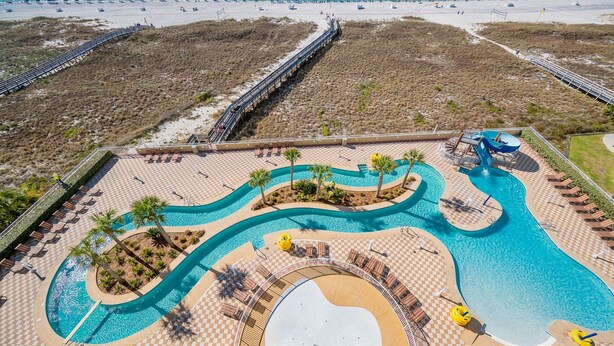 A resort with a large pool area, a beach, and a boardwalk.