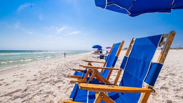 A beach with rows of blue beach chairs and umbrellas.