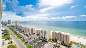 Un hotel costero con varias edificaciones, estacionamiento y vista a la playa.