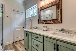 A bathroom with a large mirror, two sinks, and green cabinets. - At Last - 1011 Marquette Pl 4 Bedroom Home by RedAwning (Dauphin Island)